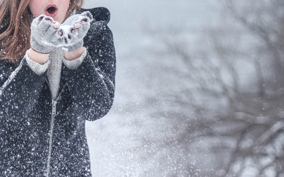 Woman blowing snow off her gloved hands