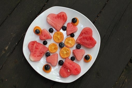 Watermelon cut into heart shapes with orange slices and blueberries