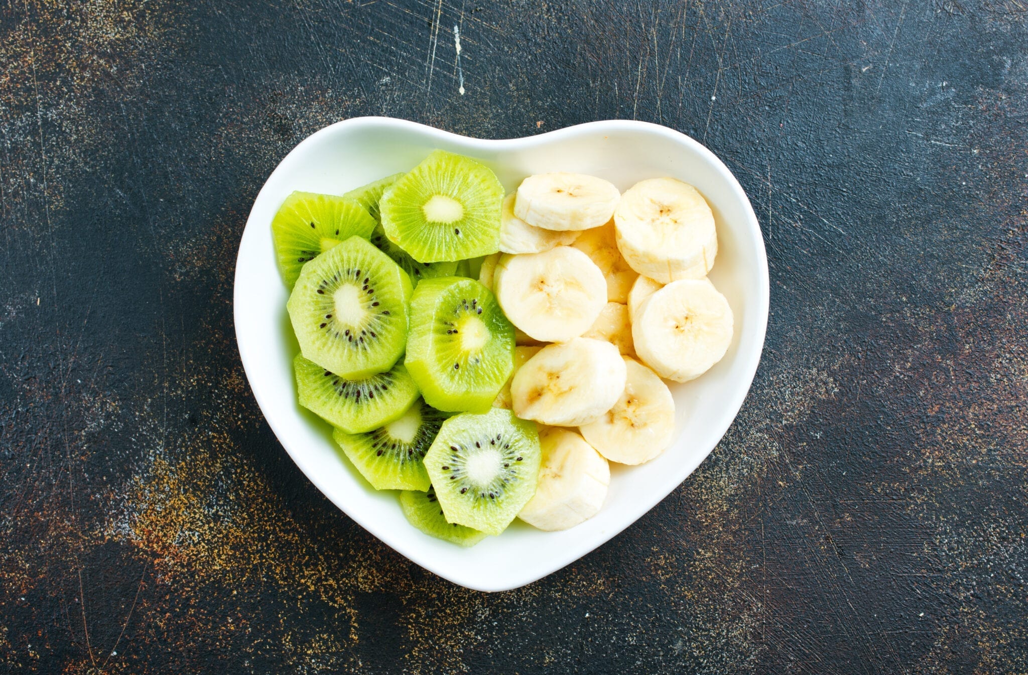 kiwis and bananas in a heart-shaped bowl