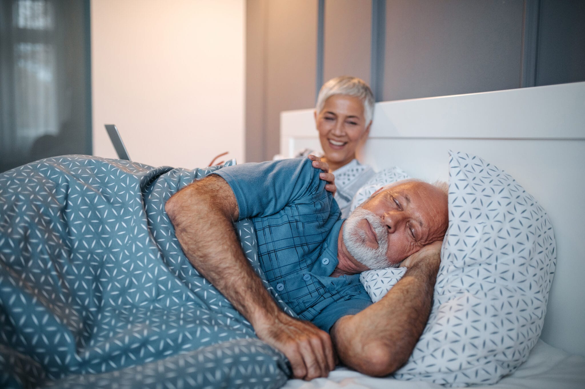 Man falling asleep next to laughing wife