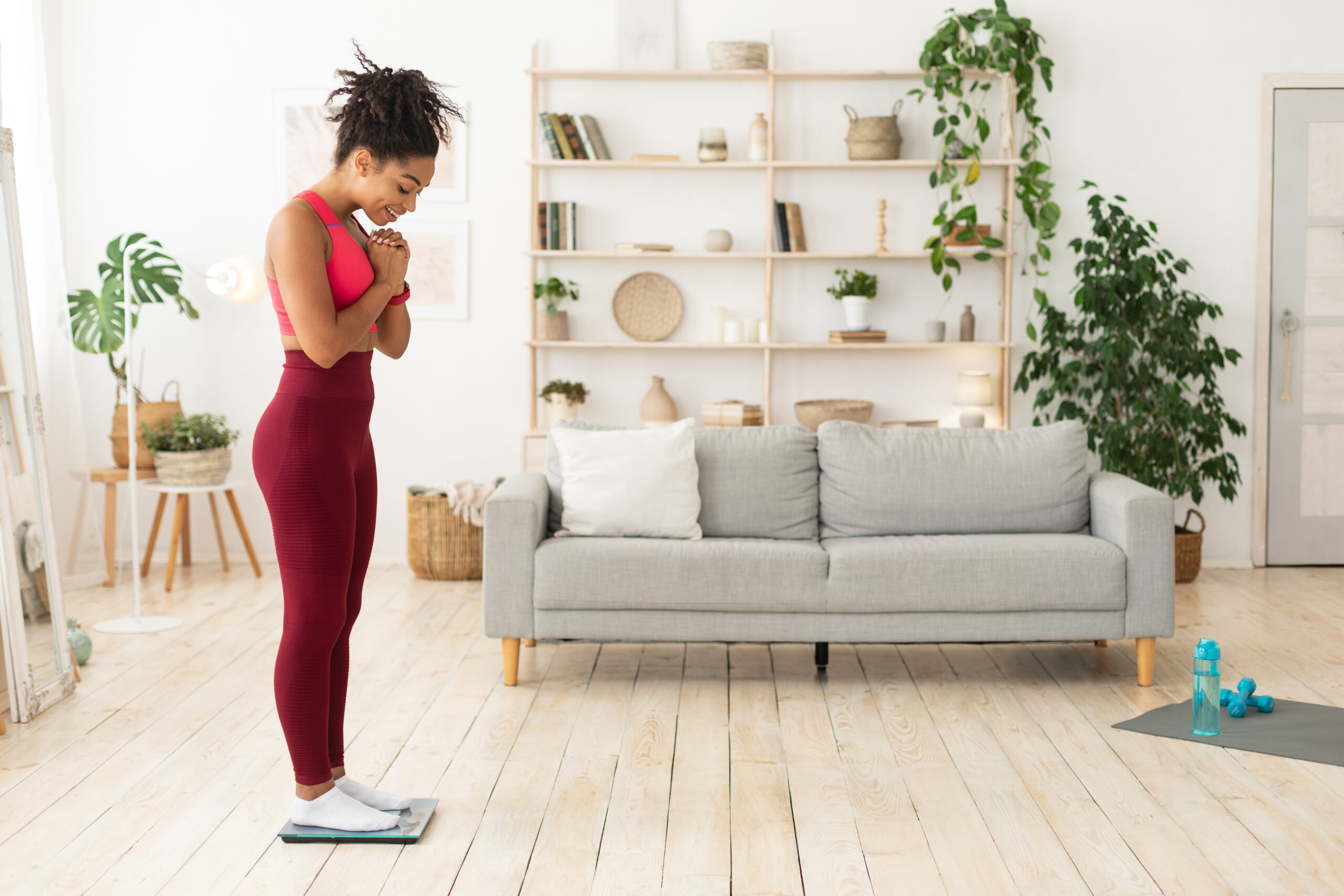 Happy Black Girl Weighing Herself On Weight Scales Losing Weight Indoor