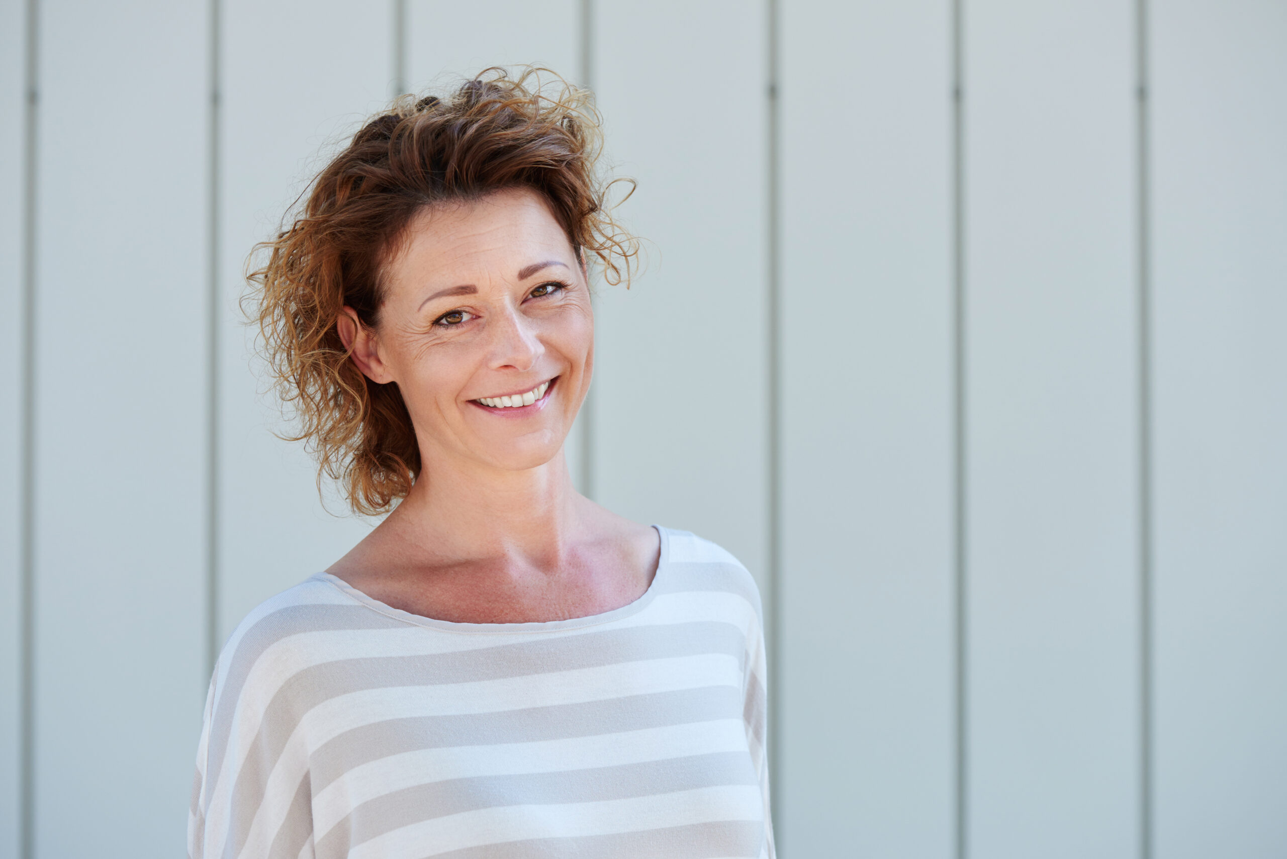 happy older woman smiling against white wall