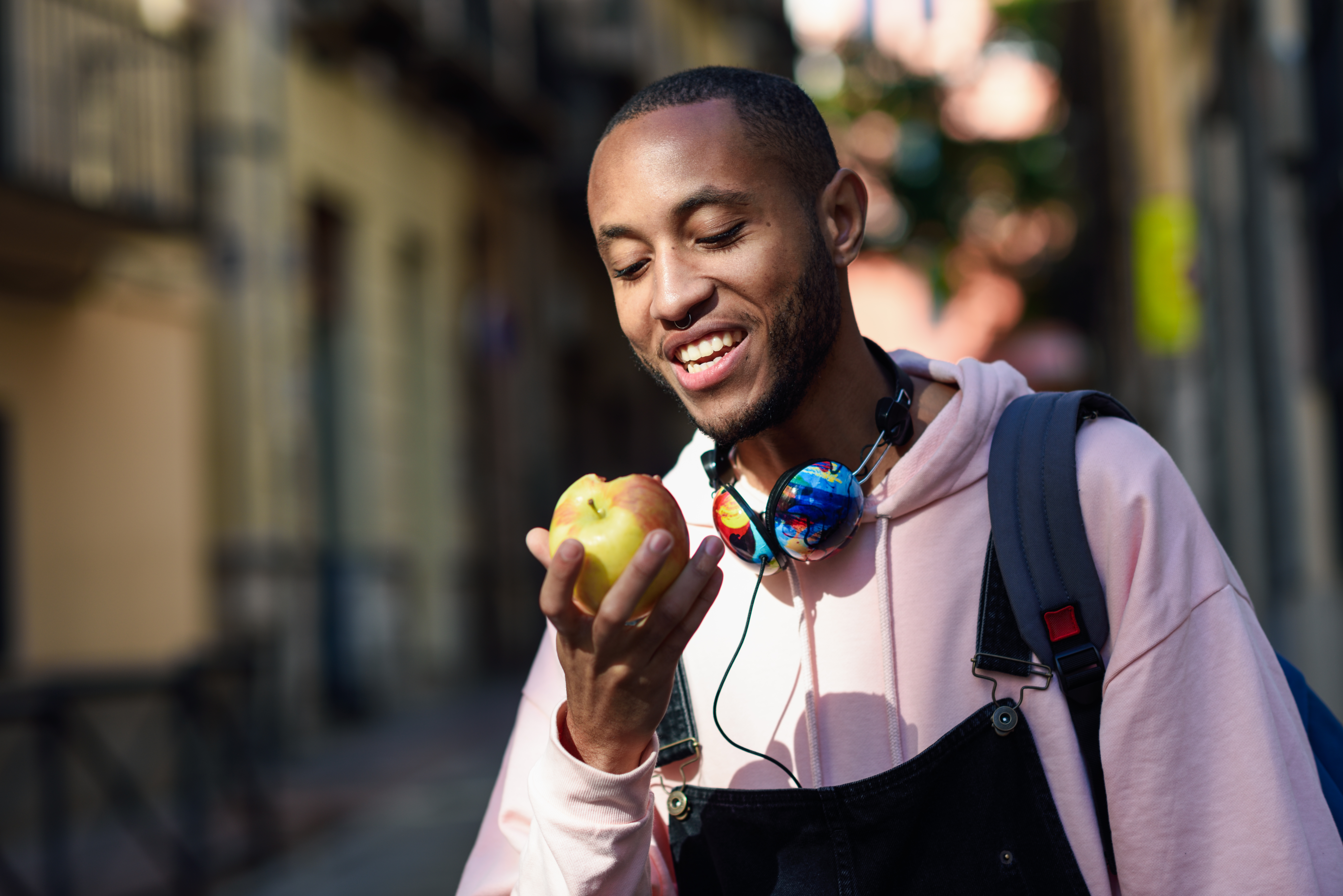 young black man eating an apple walking down the street.