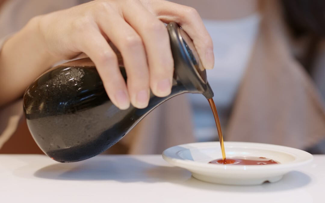 woman putting soy sauce on plate in japanese restaurant
