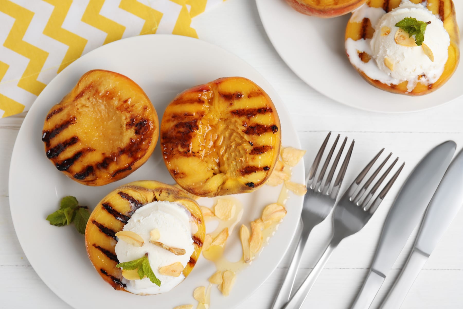 delicious grilled peaches with ice cream served on white wooden table, flat lay