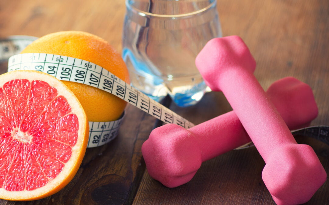 picture of items on a table including weight loss tape, hand weights, water bottle, and grapefruit