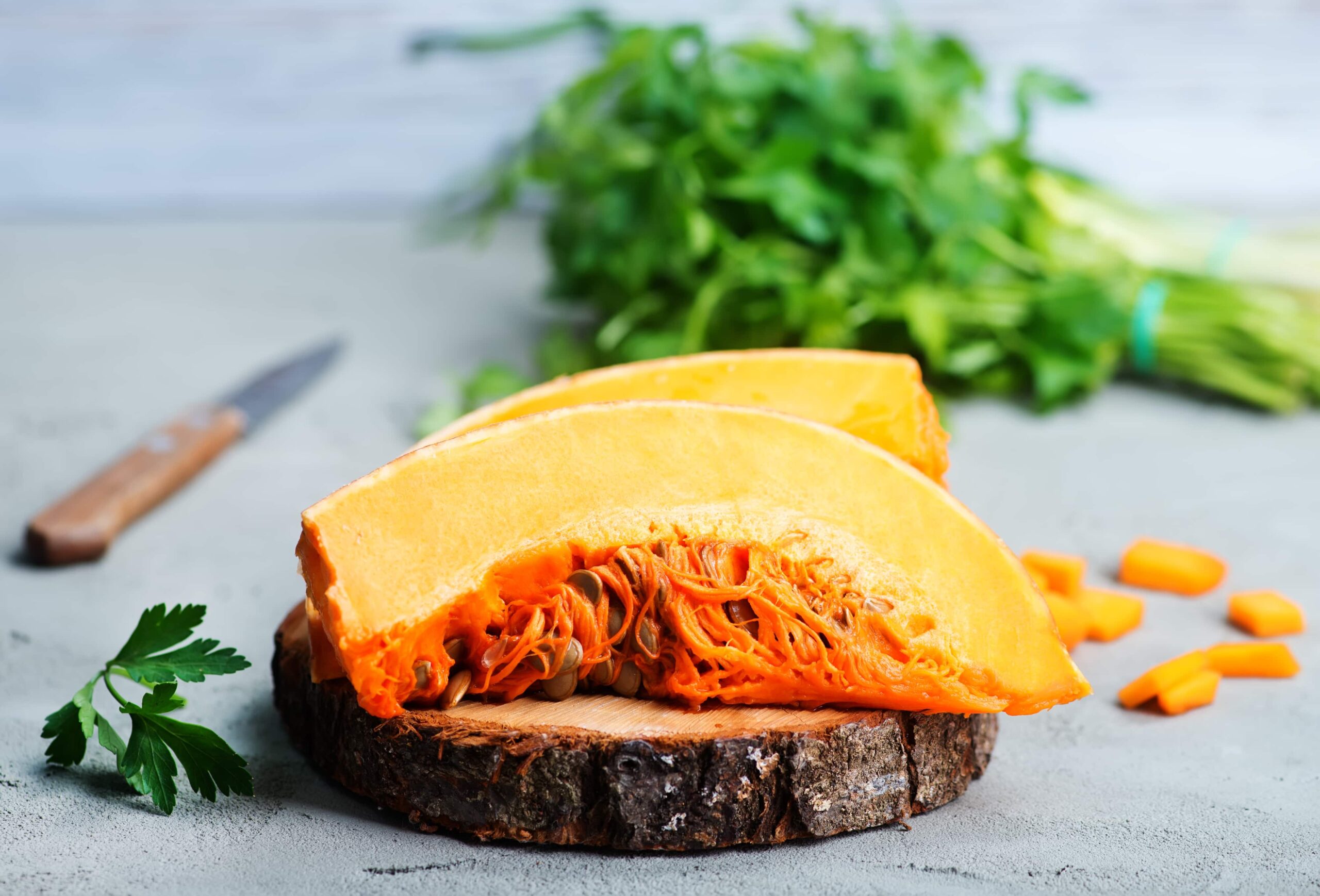 Pumpkin slice sitting on a tree trunk cutting board