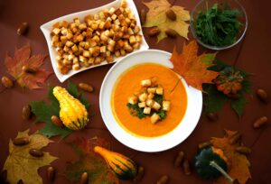 pumpkin soup with croutons surrounded by a fall scenery