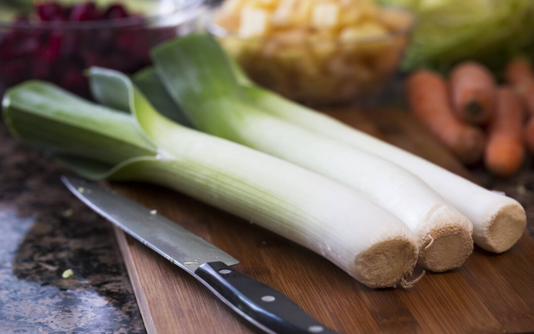 Set of leeks on a wooden cutting board with a knife