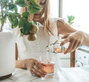 Woman pouring a glass of pink kombucha