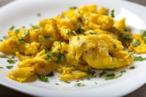 Scrambled eggs on a plate topped with freshly cut parsley
