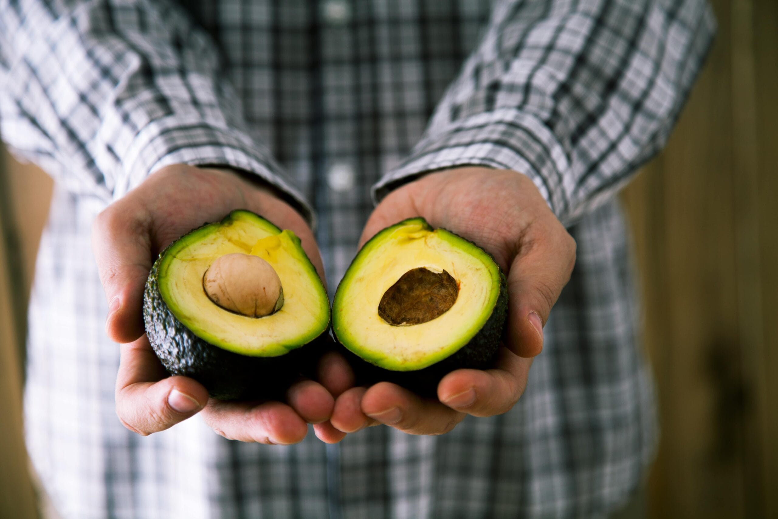 man holding cut open avocado