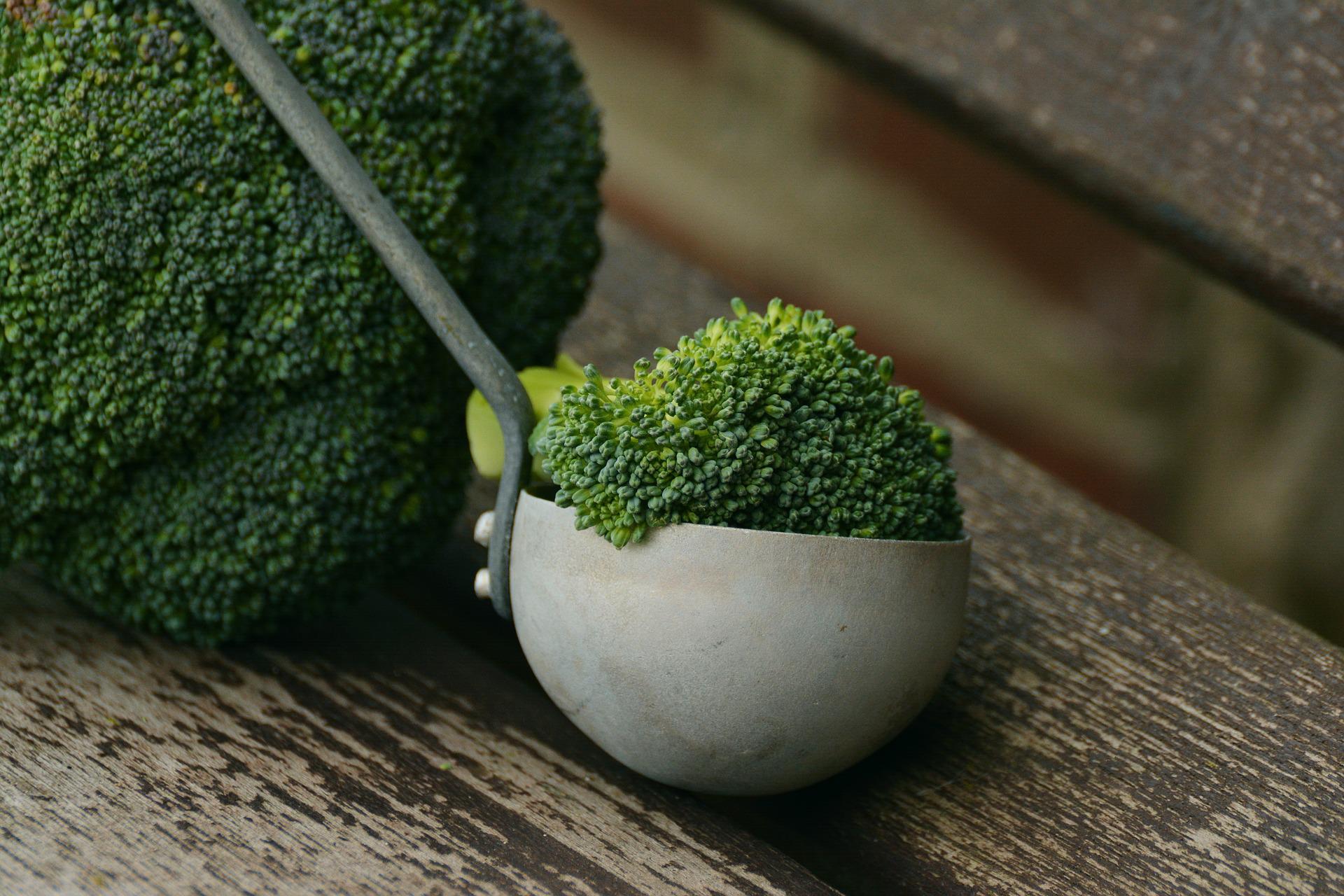 broccoli in ladle on wooden table