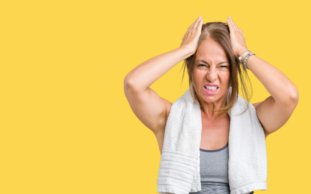 beautiful middle age woman wearing sport clothes and a towel over isolated background suffering from headache desperate and stressed because pain and migraine. hands on head.