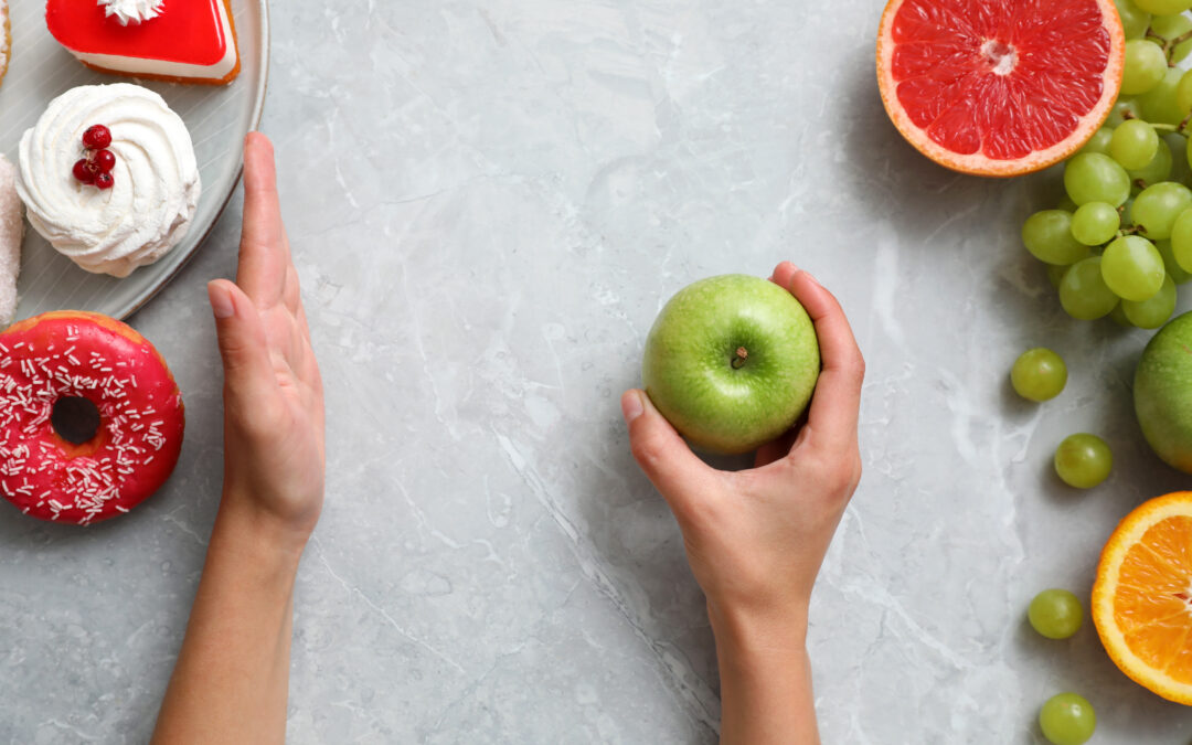 top view of woman holding apple at grey table, closeup