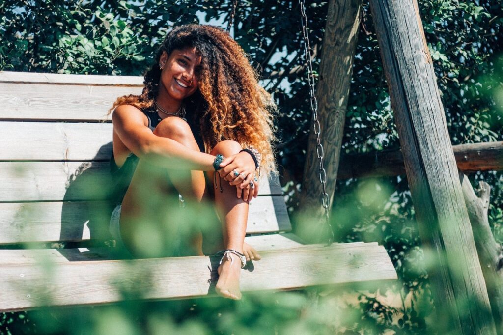 young woman sitting on bench in sun showing skin