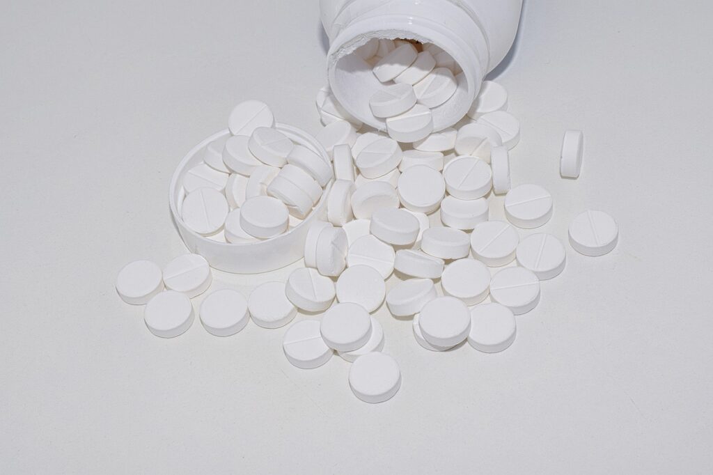 magnesium_supplement_white_circular_pills_spilled_from_bottle_on_white_table