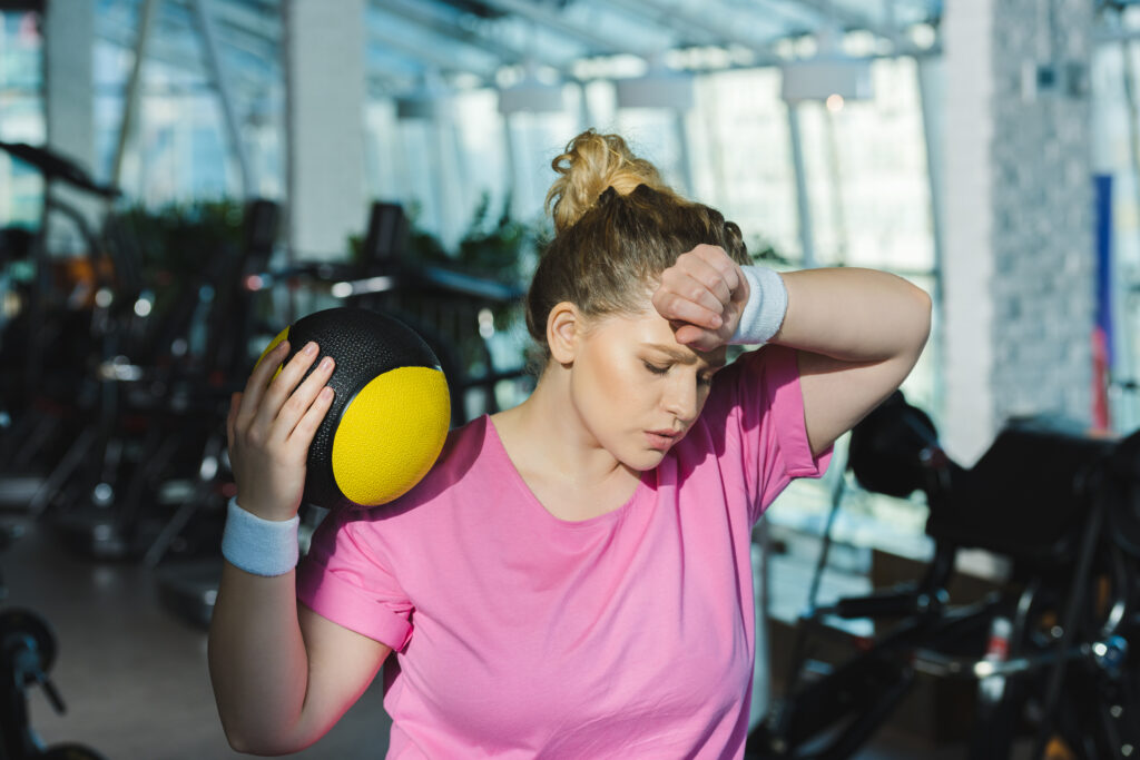 woman at the gym tired wiping sweat from her forhead as she tried to work hard and get healthy