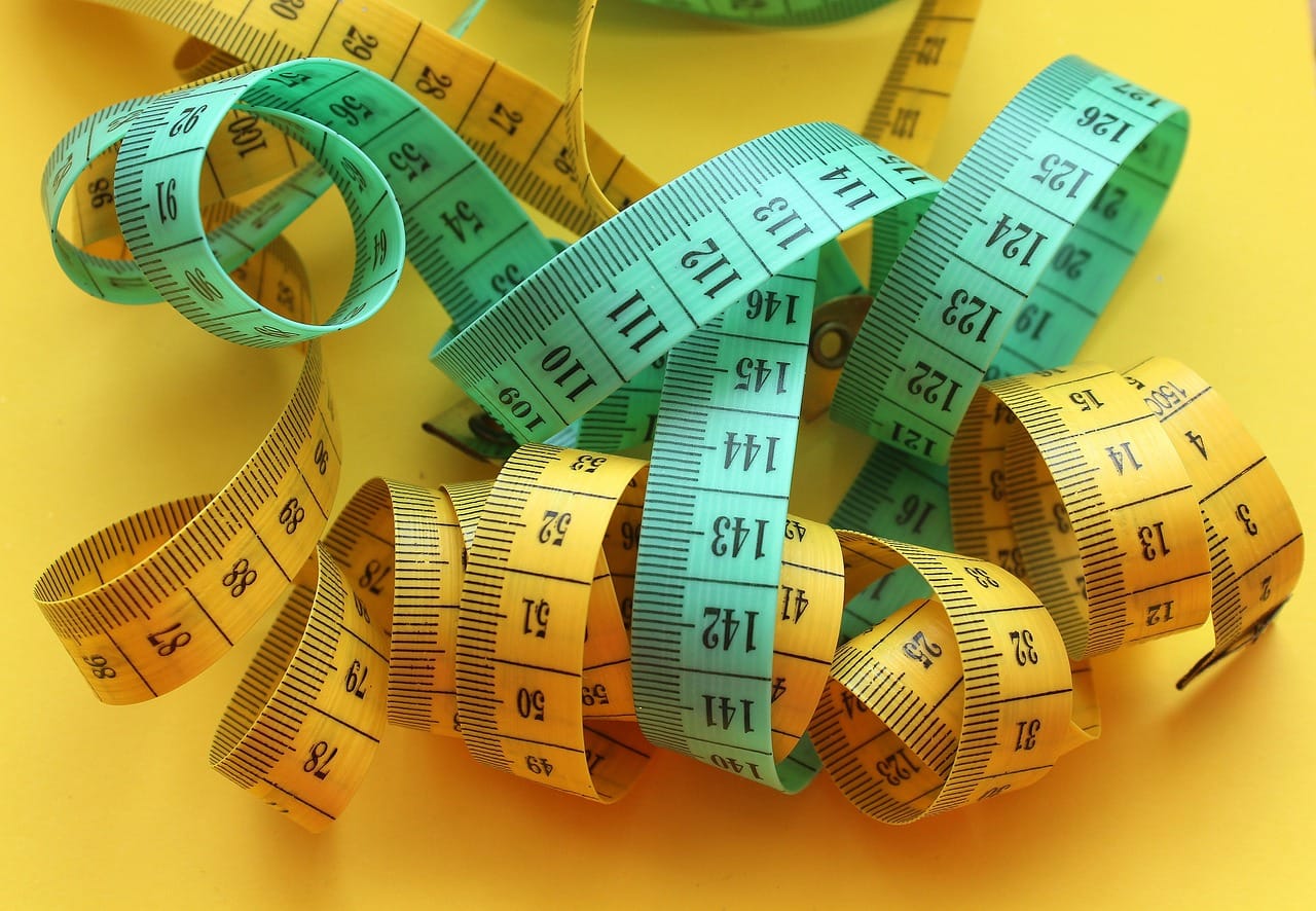 blue and yellow tape measures tangled up on yellow table