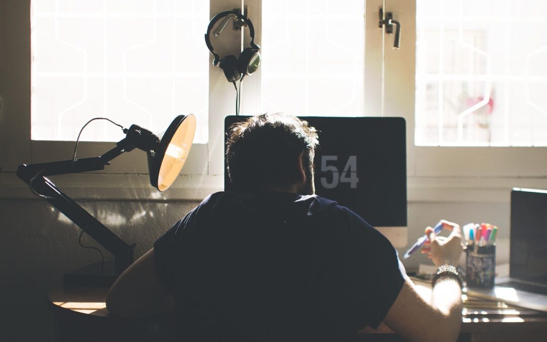 man hunched over sitting at home desk working
