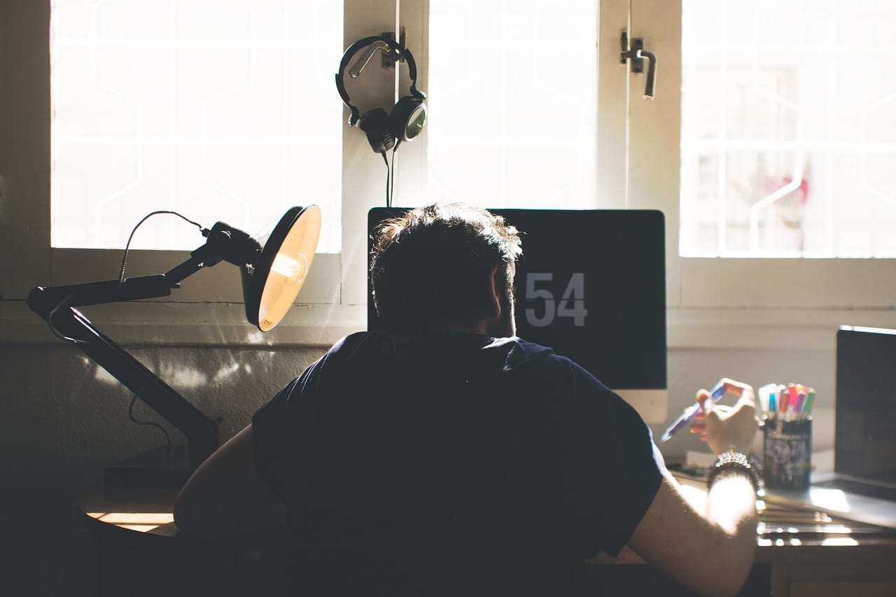 man hunched over sitting at home desk working