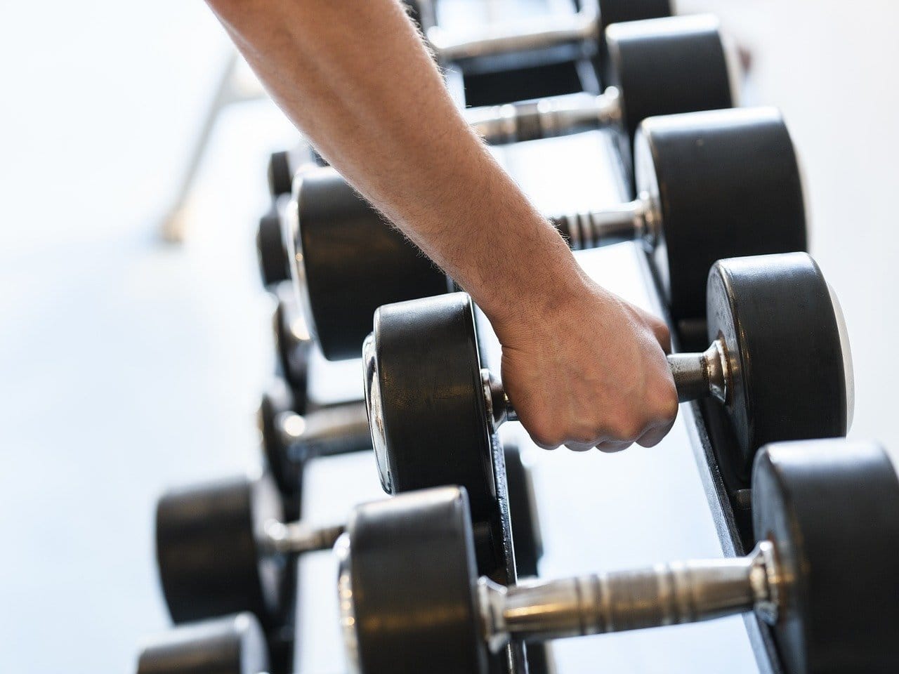 male forearm grabbing weight from weight rack