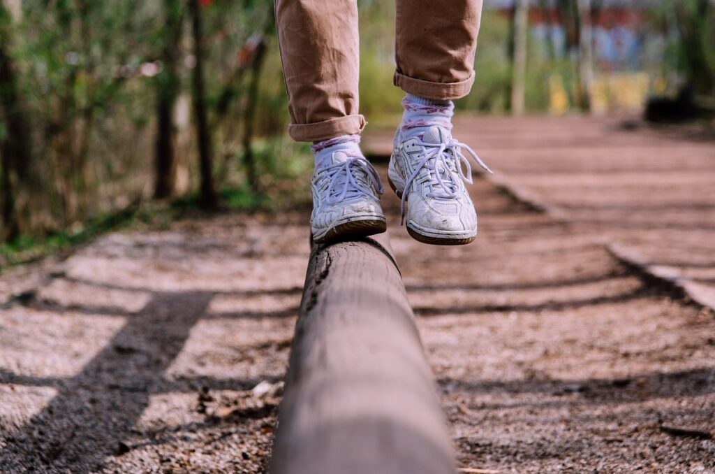 person balancing on wooden beam