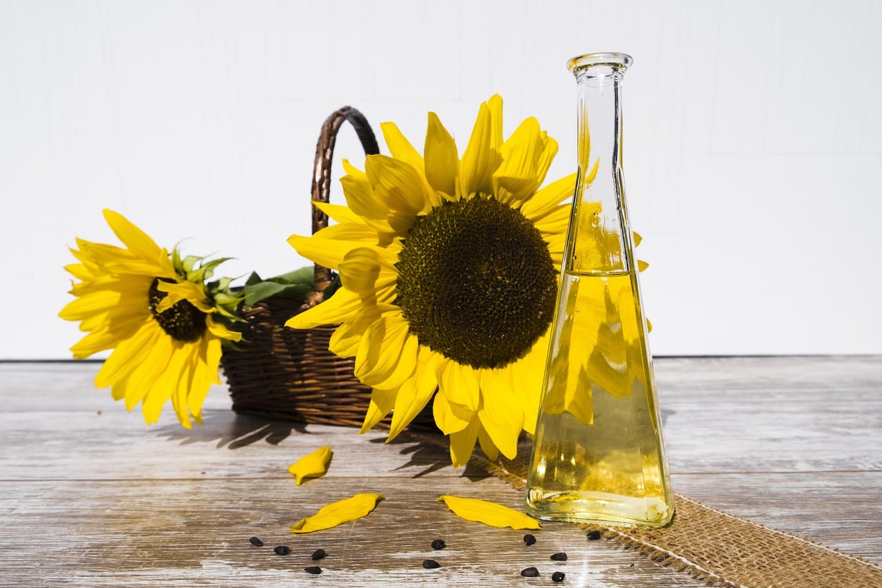 basket of sunflowers and bottle of sunflower oil on table