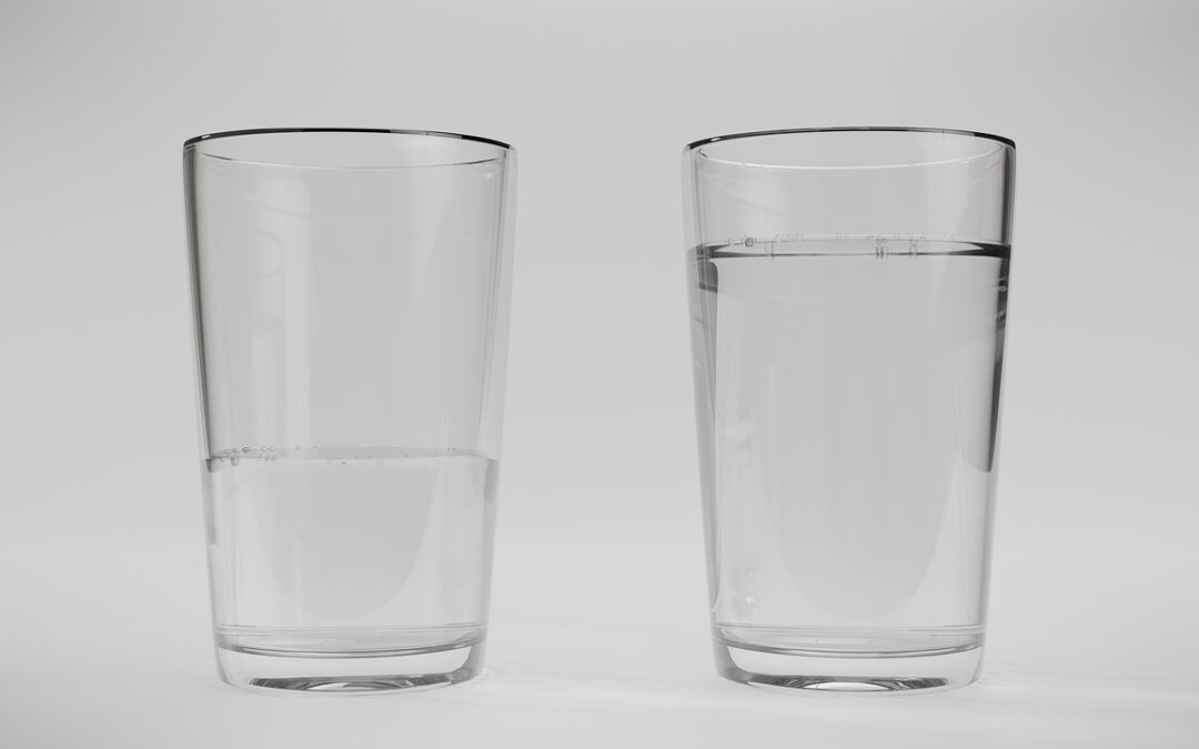 two water glasses one full and one half empty on a white background