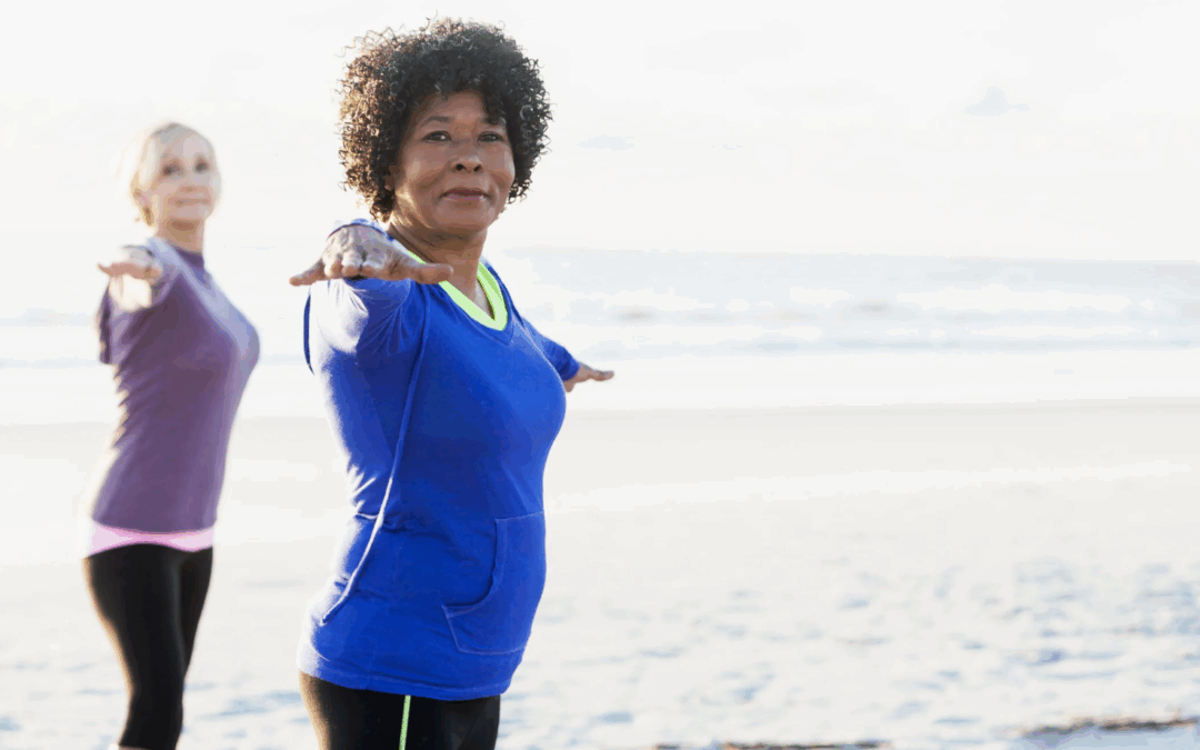 two older women over 50 doing yoga on the beach