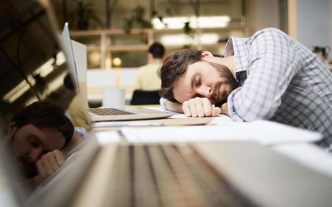 tired man falling asleep at work desk in front of computer