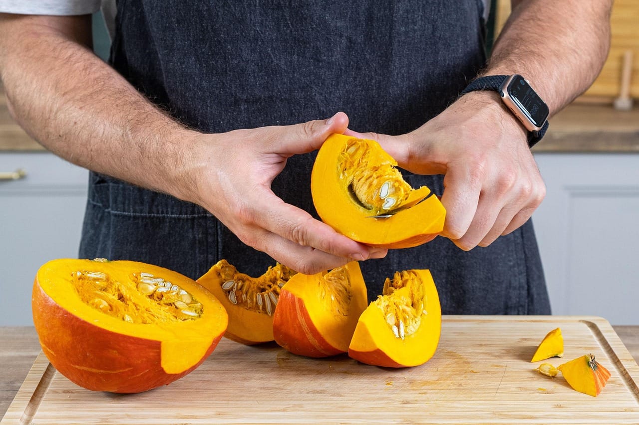 man cutting pumpkin up and removing pumpkin seeds